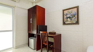 A compact office space with a desk, chair, and a small refrigerator. - OYO 604 Queen Hotel (Hanoi)