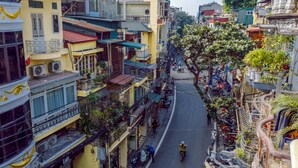 A narrow street lined with multi-story buildings, some with balconies and air conditioning units. - OYO 604 Queen Hotel (Hanoi)