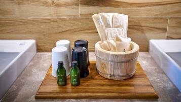 A wooden tray with bath products, including bottles and a wooden bowl, on a countertop in a bathroom.