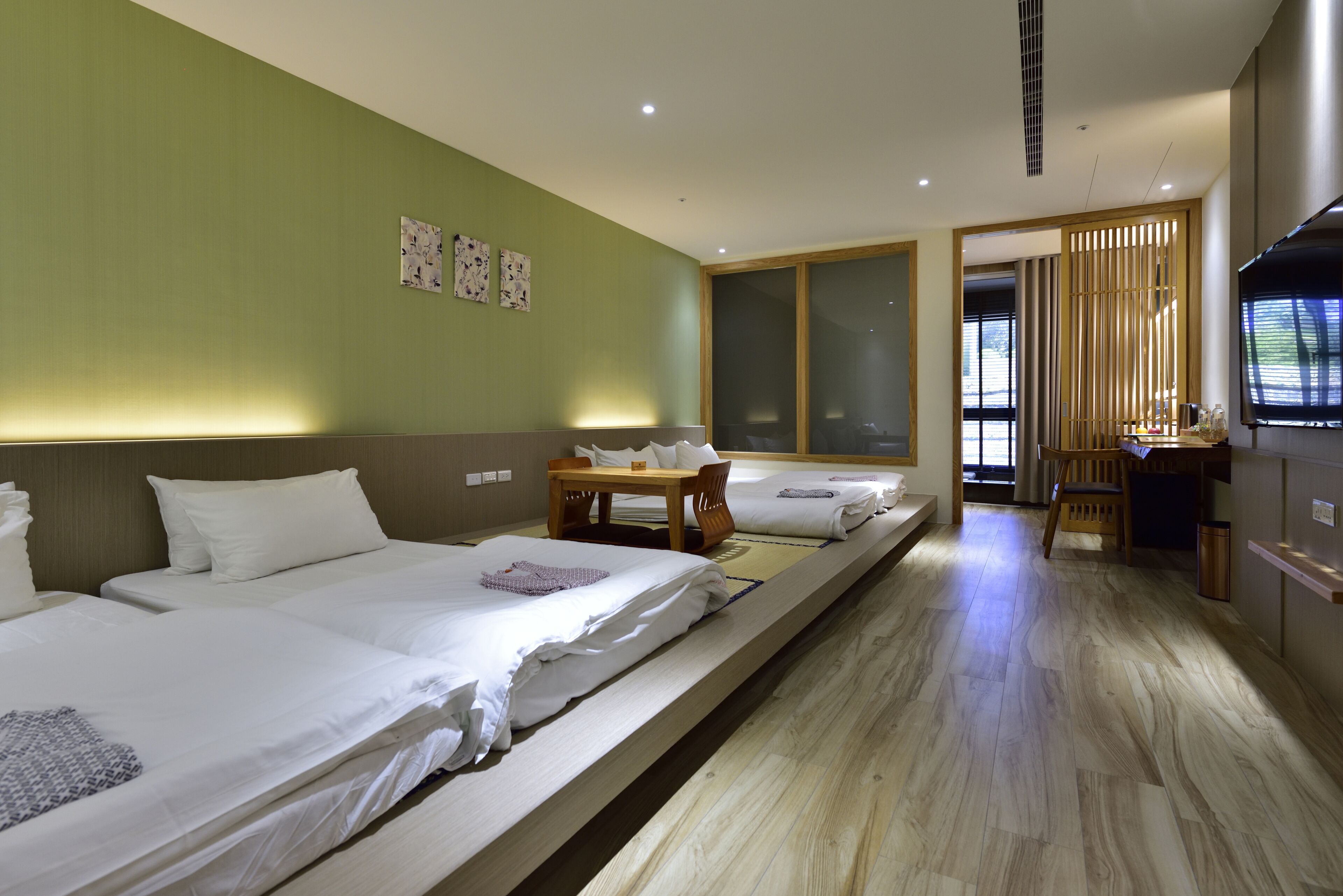 Une chambre d’hôtel avec deux lits, un plancher en bois, une télévision et un bureau avec une chaise.