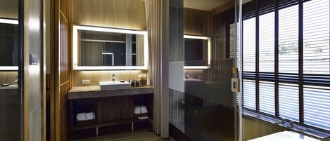 A modern bathroom with a wooden vanity, a large mirror, and a glass-enclosed shower area.