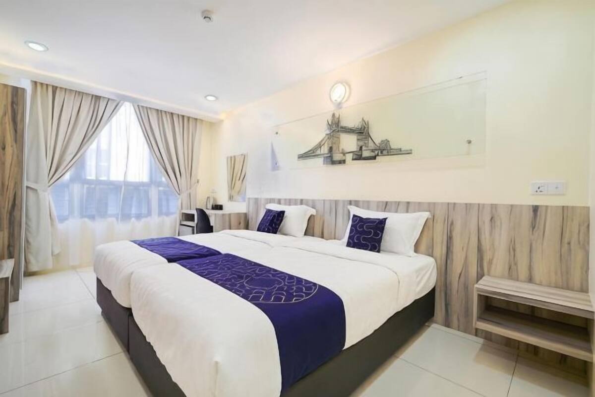 Una habitación de hotel con una cama grande, mesitas de noche, un escritorio y una silla.