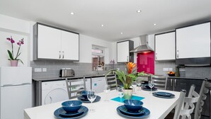 Een moderne keuken met witte kasten, een centraal eiland met blauwe borden en glazen, en een roestvrijstalen afzuigkap.