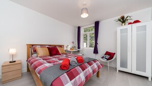 Een netjes ingerichte slaapkamer met een bed, nachtkastje, lamp en een kledingkast.