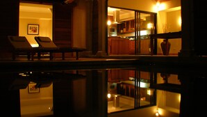 A dimly lit room with a pool reflecting the interior. There are two lounge chairs and a framed picture on the wall. - Villa Oasis 1 no 7 (Grand-Baie)