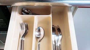 Un cajón con compartimentos que contiene tenedores, cucharas y un cuchillo.