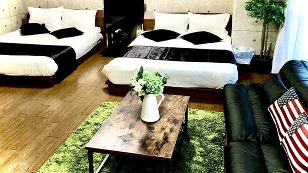 Una sala de estar moderna con dos camas, una mesa de centro con un florero, un sofá y un ventanal grande.
