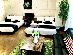 Una sala de estar moderna con dos camas, una mesa de centro con un florero, un sofá y un ventanal grande.