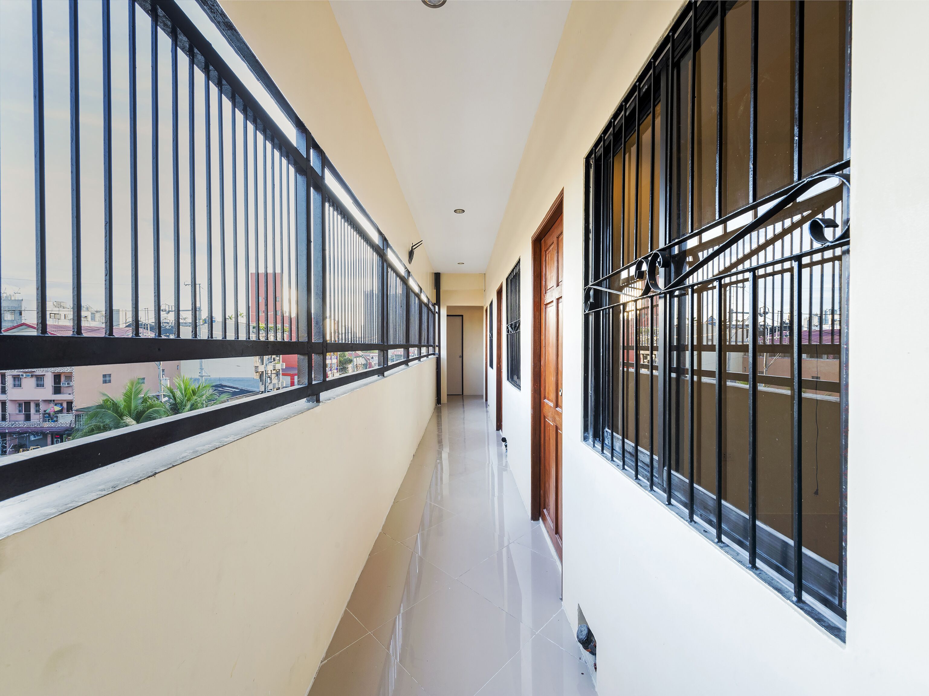 A narrow corridor with metal railings and large windows on both sides, leading to a door.
