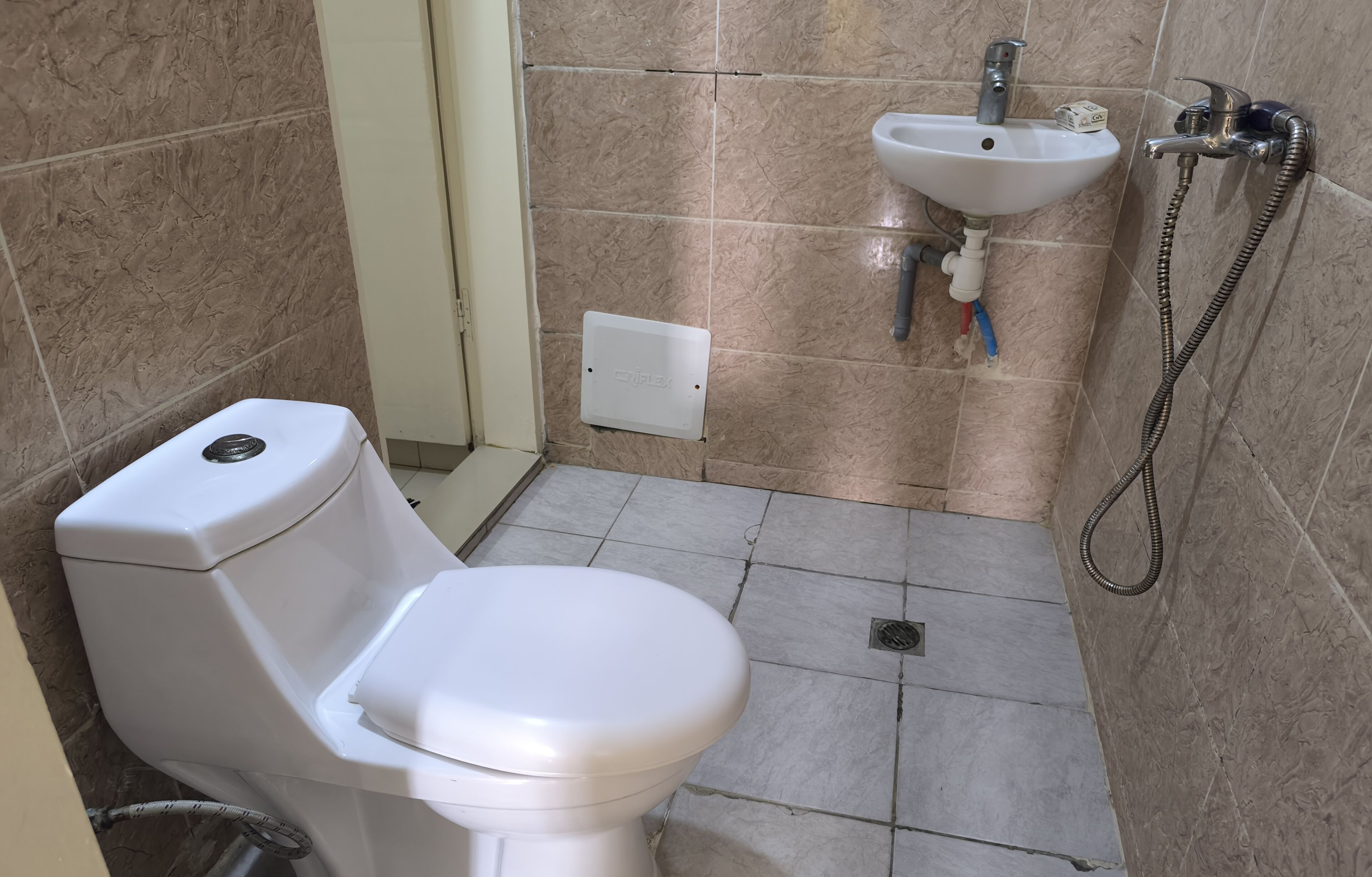 A small bathroom with a toilet, sink, and shower.