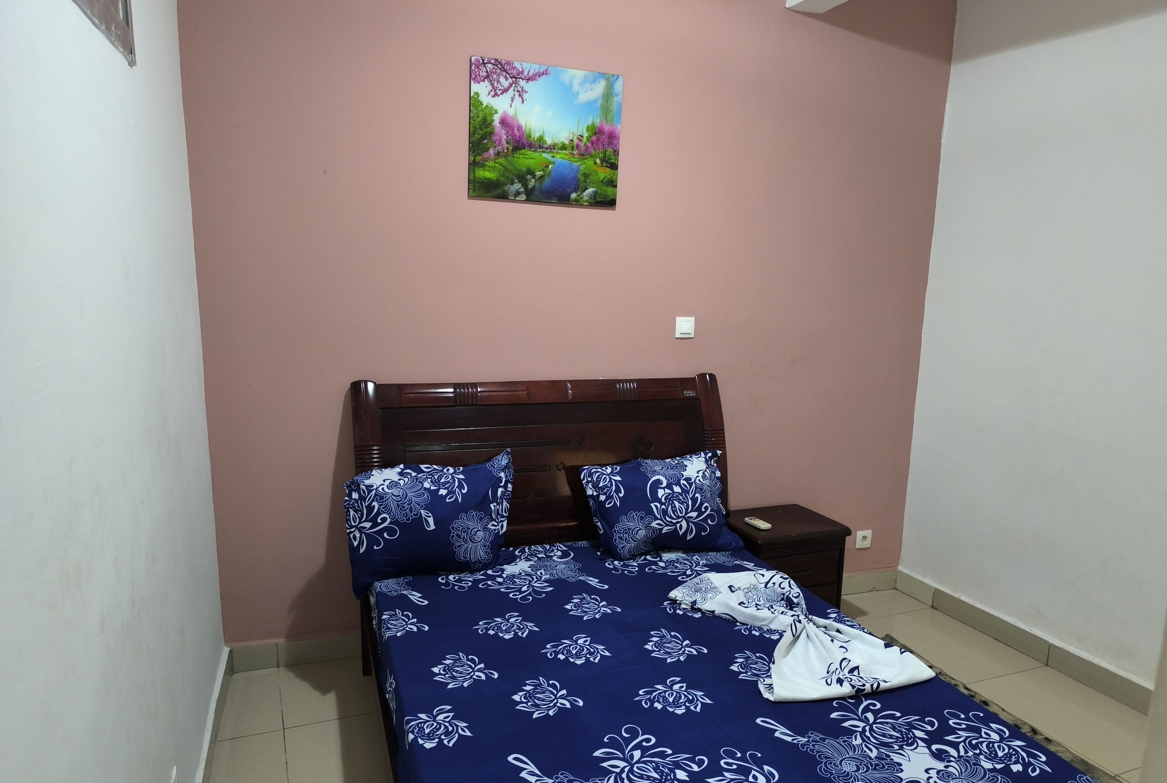 Une chambre à coucher avec un lit, une table de chevet et un tableau accroché au mur.