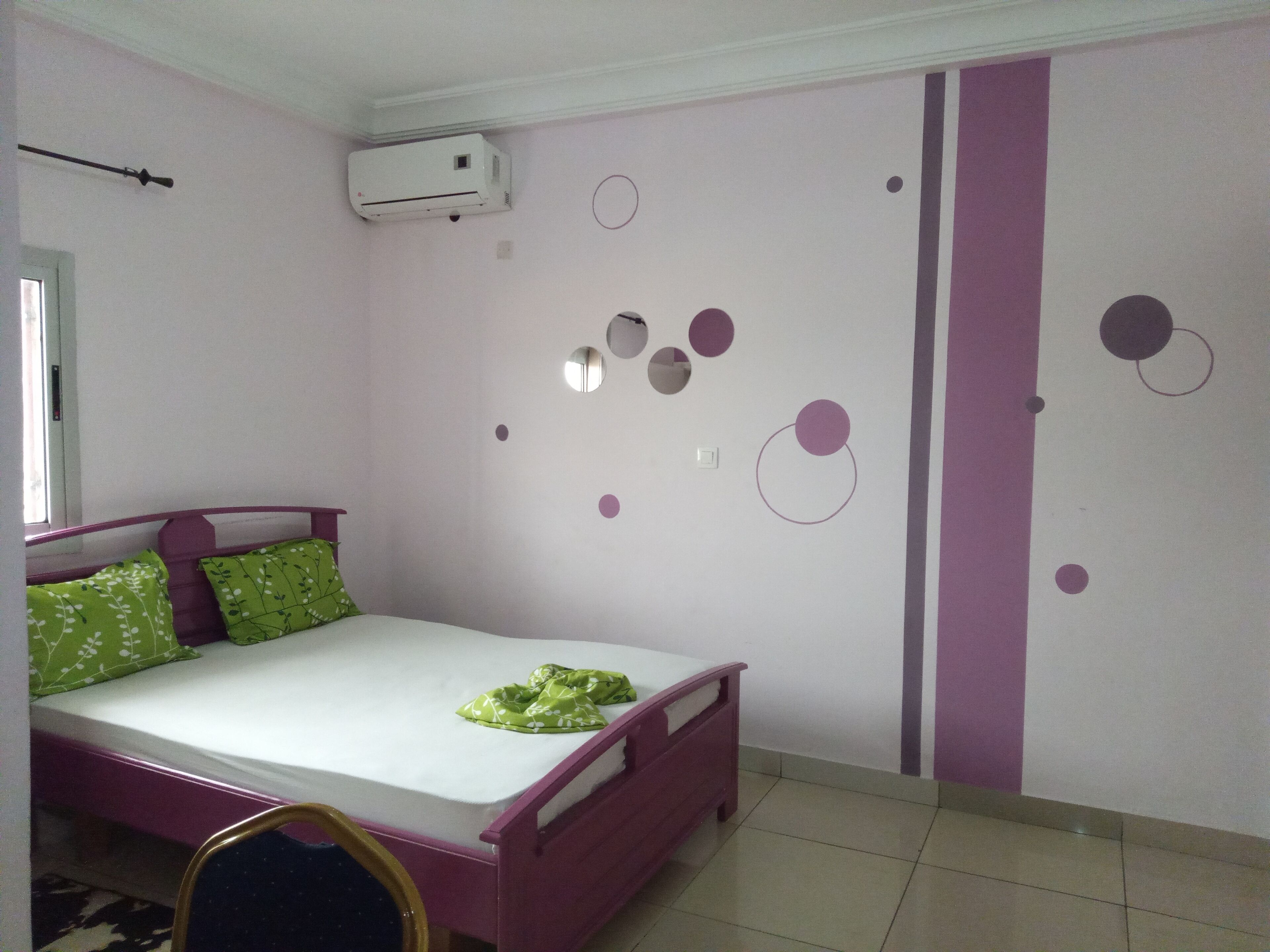 A bedroom with a bed, a window, and a wall-mounted air conditioner.