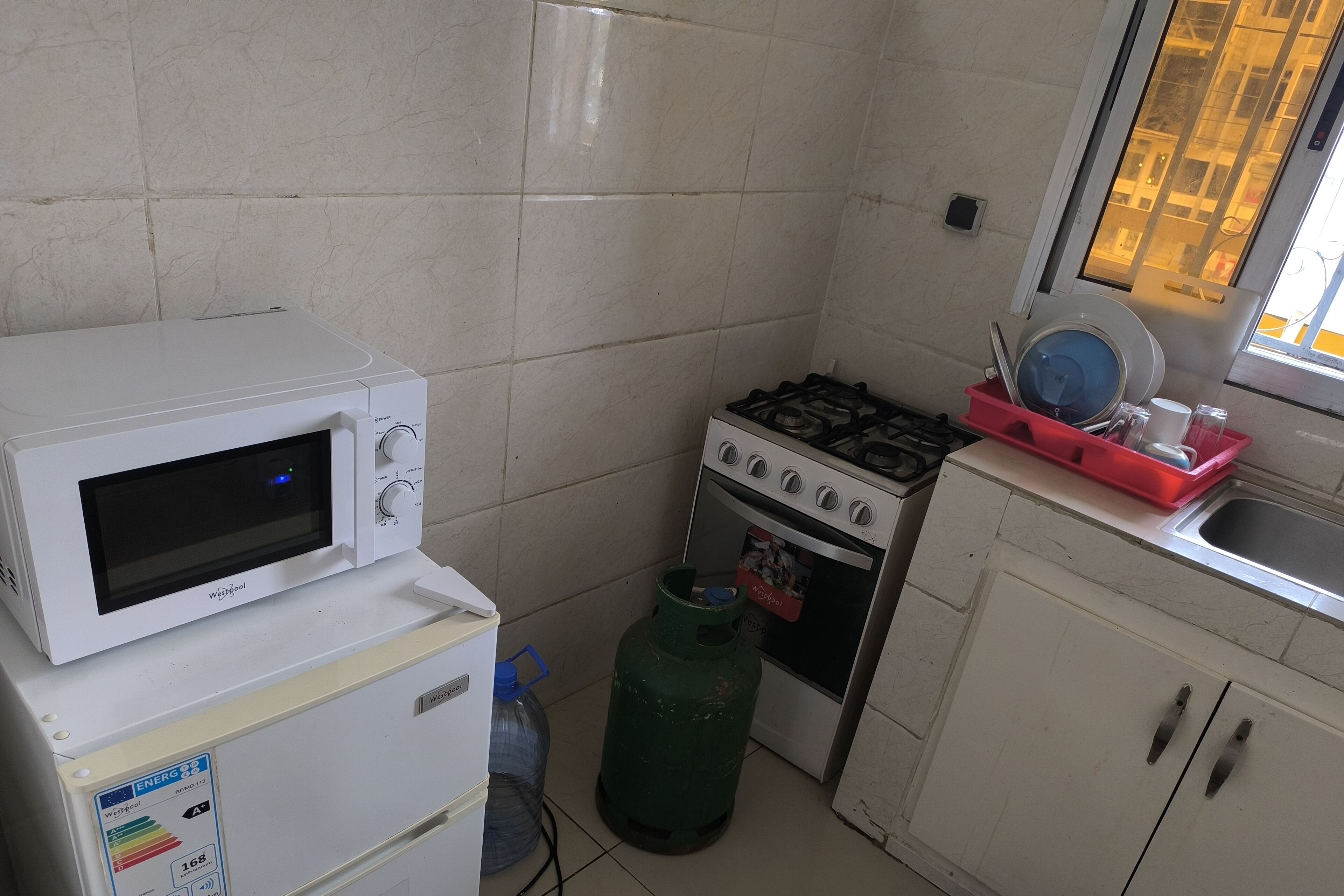 A compact kitchen with a microwave, gas stove, and a water dispenser.