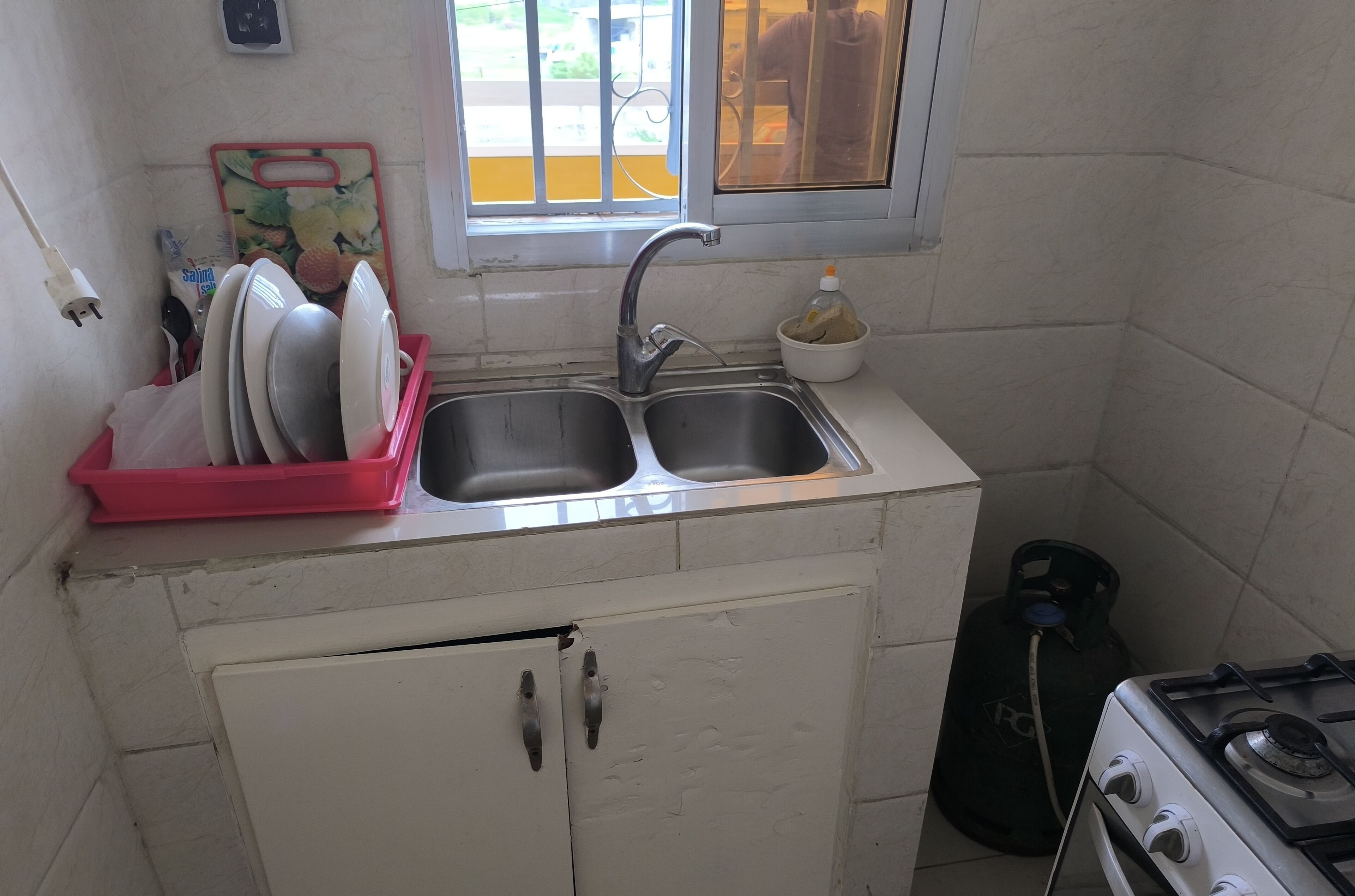 Una cucina compatta con lavandino, piano cottura a gas e un piccolo armadietto.