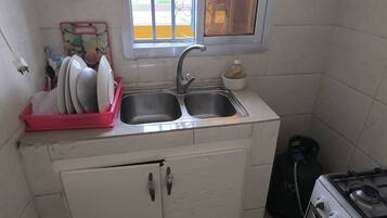 Una cucina compatta con lavandino, piano cottura a gas e un piccolo armadietto.