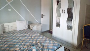 A bedroom with a bed, a wardrobe, and a nightstand. - Résidence Gian (Libreville)