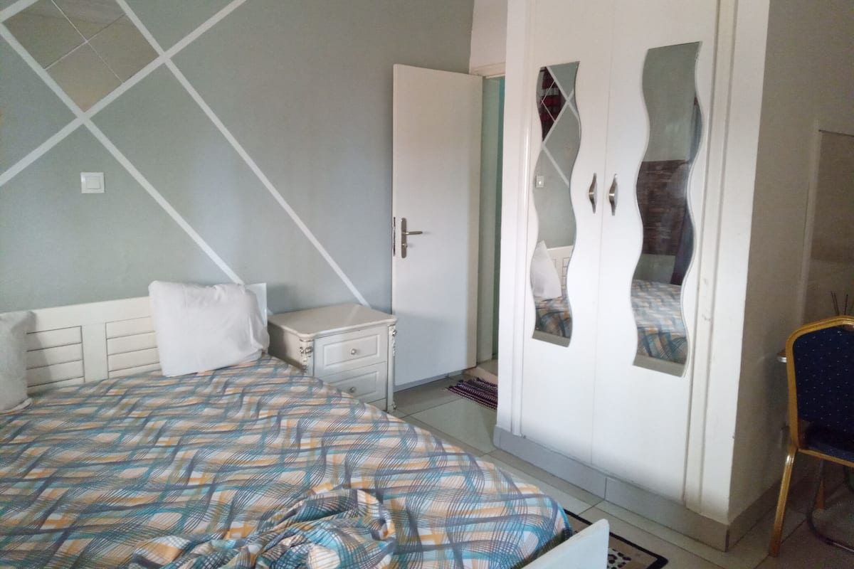 Quarto com cama, guarda-roupa e mesa de cabeceira.