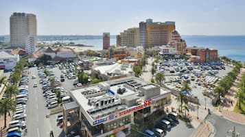 Una calle urbana concurrida con una destacada casa de carne y varios edificios, incluyendo un hotel alto y vistas al mar.