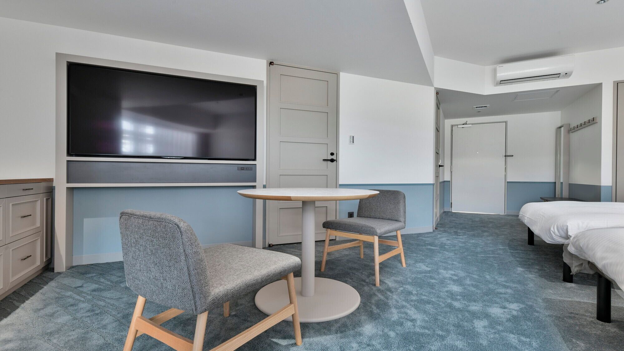 Una habitación de hotel con televisión, dos sillas, una cama y una mesita.