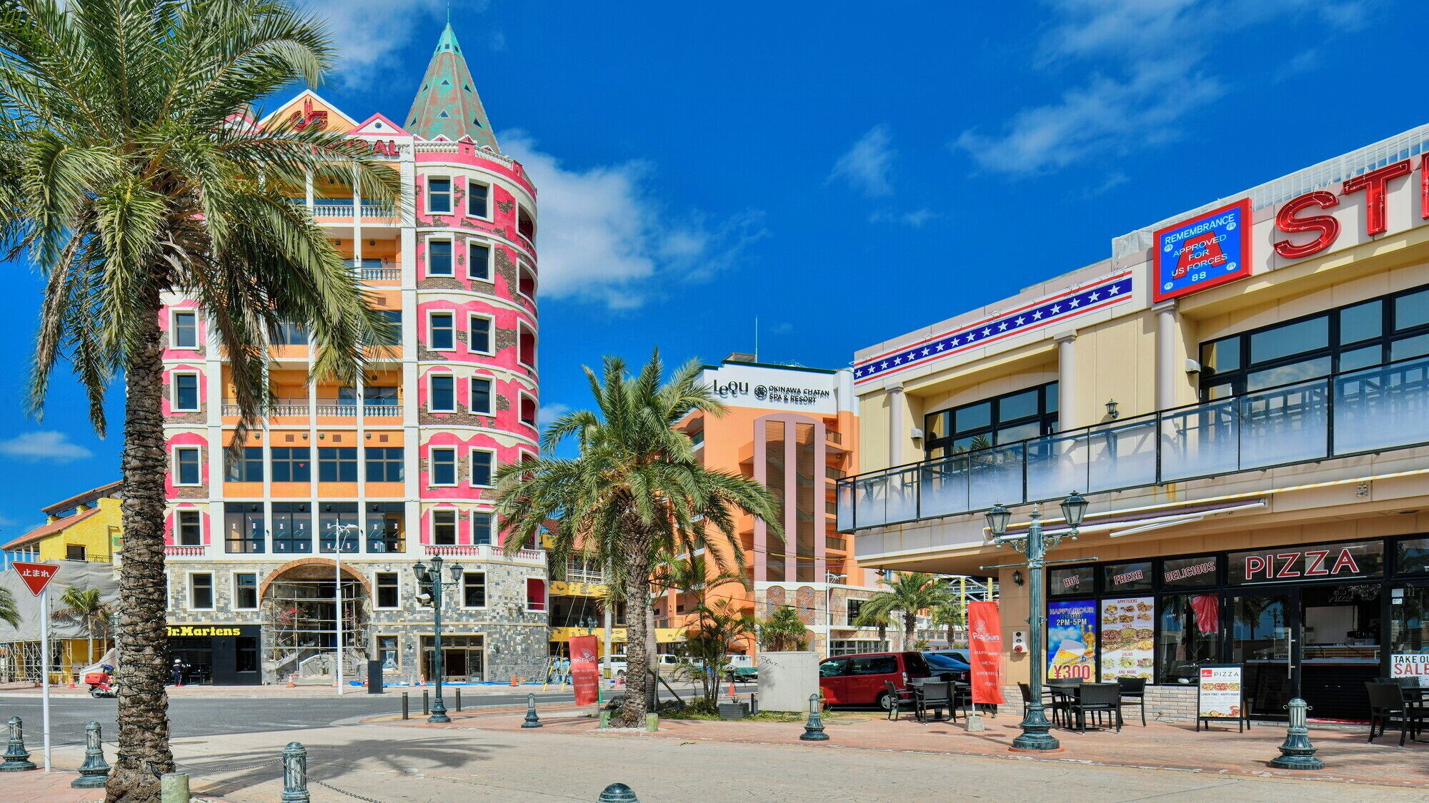 A colorful hotel with a distinctive pink and orange facade, a prominent tower, and a spa & resort sign.