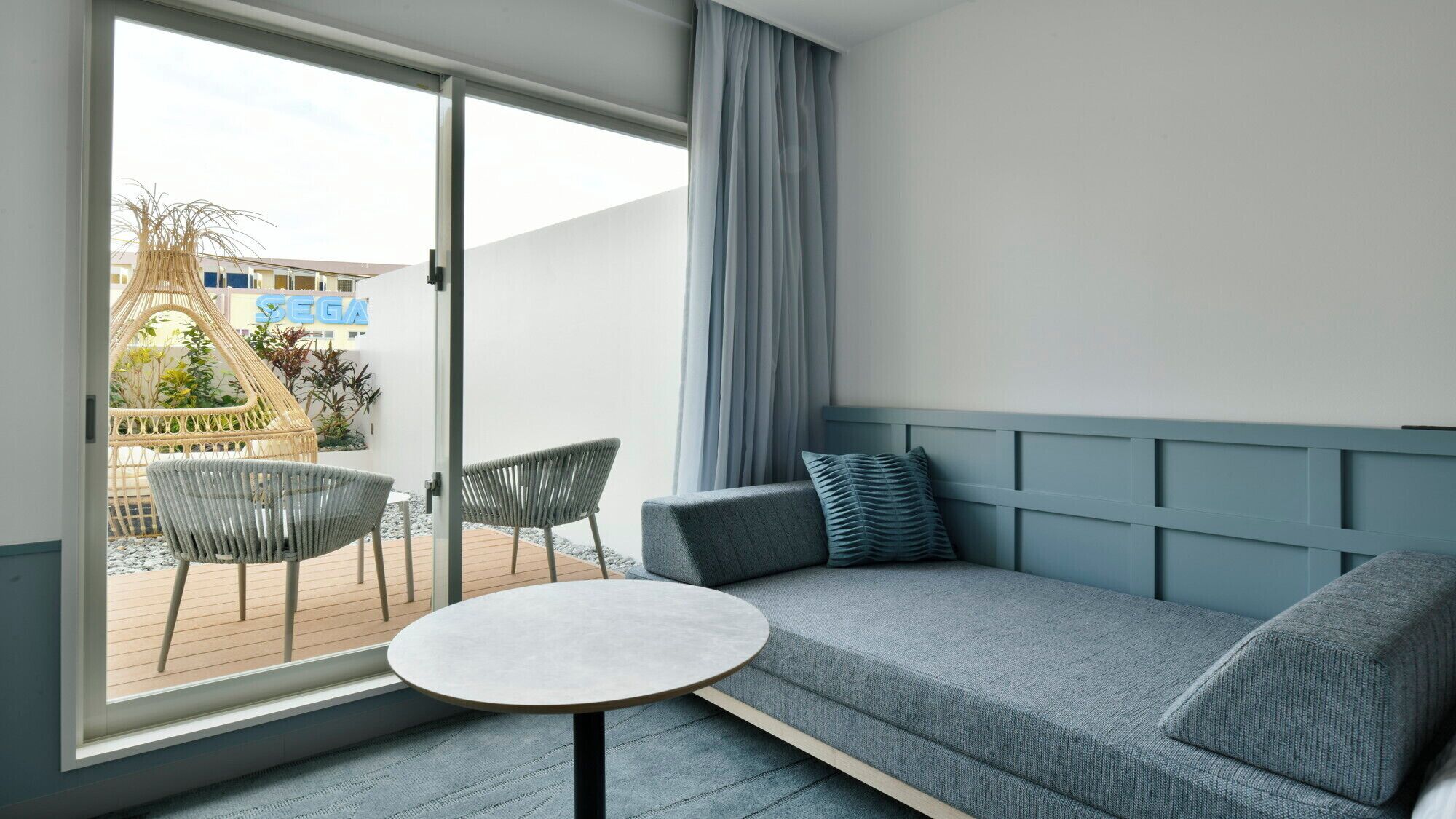 Una habitación moderna con un sofá gris, dos sillas y una mesita.