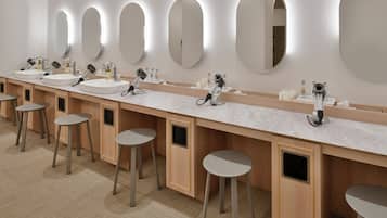 Uma casa de banho moderna com várias bacias, espelhos e bancos.