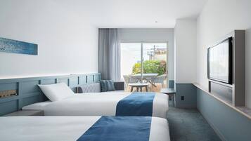 Habitación de hotel con dos camas, televisión, balcón con mesa y sillas, y un cuadro en la pared.