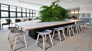 Un moderno bar con una barra larga, varios taburetes y una gran planta verde como elemento decorativo.
