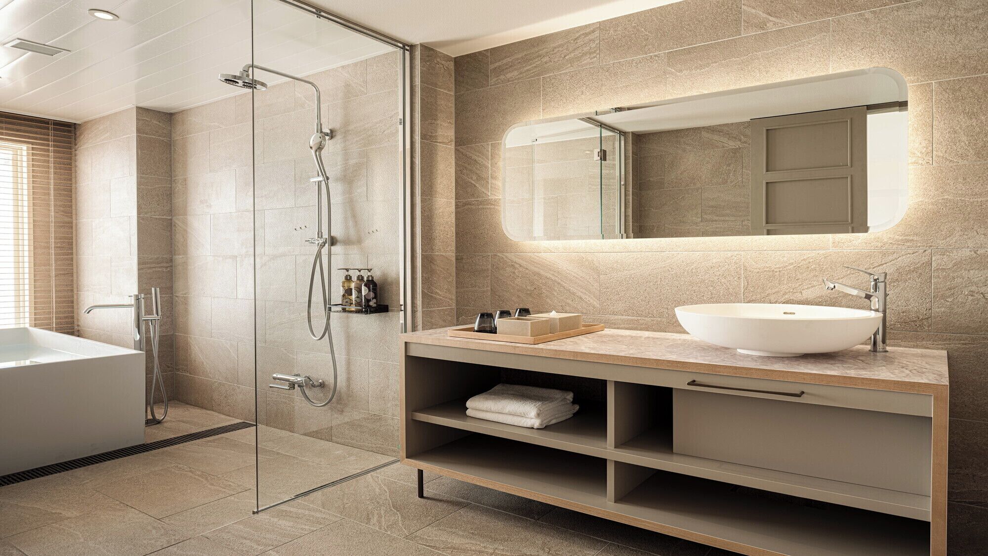 A modern bathroom with a glass-enclosed shower, a freestanding bathtub, a vanity with a large sink, and a mirror above the vanity.