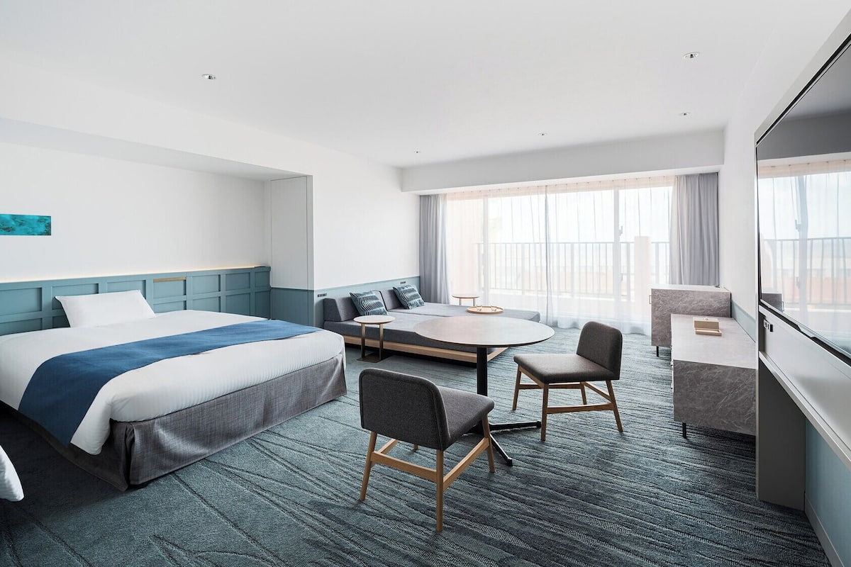 A hotel room with two beds, a small table, a chair, and a desk.