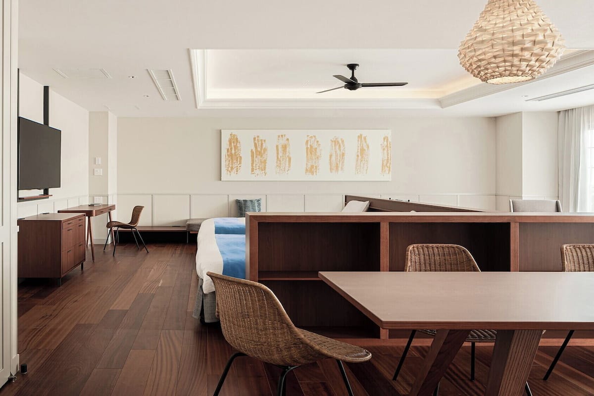 A modern, open-plan living space with a dining area, a sofa, a TV, and a ceiling fan.