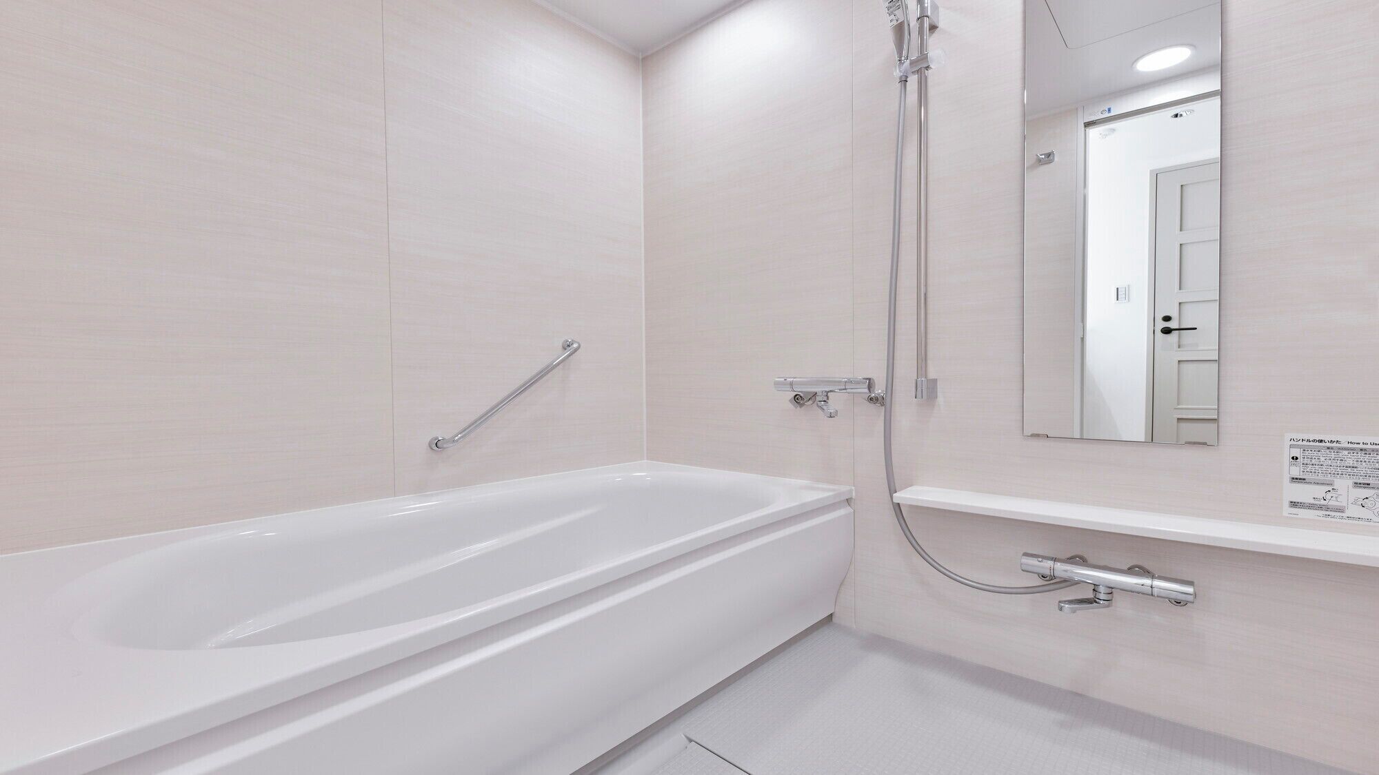 A modern bathroom with a white bathtub, a shower with a handheld showerhead, and a wall-mounted mirror.