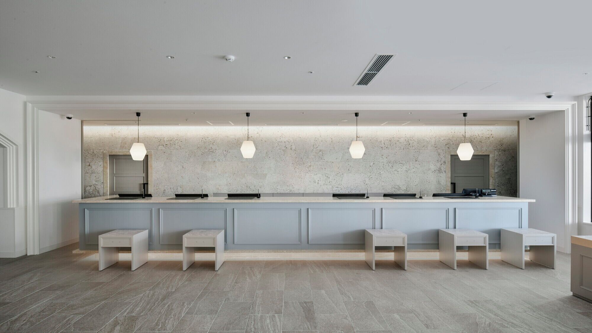 Une cuisine moderne avec un revêtement mural en marbre, des luminaires suspendus et un îlot central doté de tabourets.