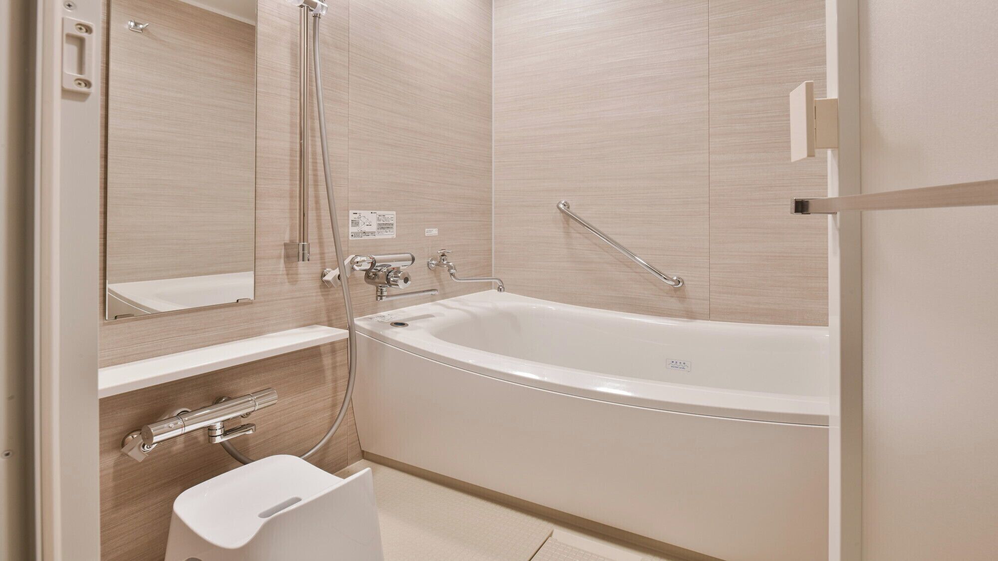 A modern bathroom with a freestanding bathtub, a built-in vanity, and a handrail.