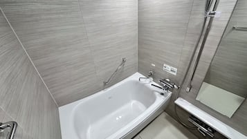 Un baño moderno con una bañera independiente, un cabezal de ducha manual, un perchero y un box de vidrio.