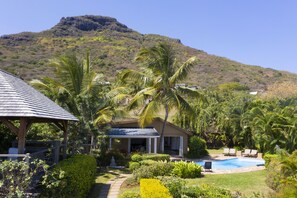 A resort with a pool, palm trees, and a mountain backdrop.