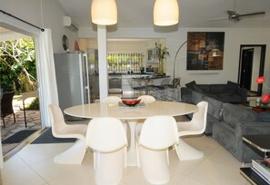 A modern kitchen with a dining area, a grey sofa, and a large window.