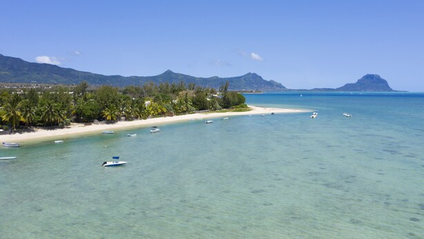 A beach with clear turquoise water, boats, and a mountain in the background. - Villa Acassia with 2 rooms (Black River)