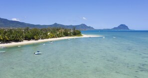 A beach with clear turquoise water, boats, and a mountain in the background. - Villa Acassia with 2 rooms (Black River)