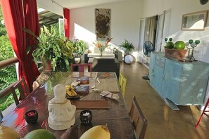A dining area with a table set for four, surrounded by chairs, a blue cabinet, and various decorative items. - Villa de la Valle (Rodrigues Island)