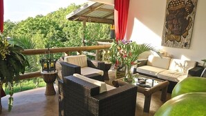 A cozy outdoor seating area with wicker furniture, a coffee table, and potted plants.