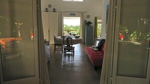 A room with a dining table, chairs, a red sofa, and an exit sign.