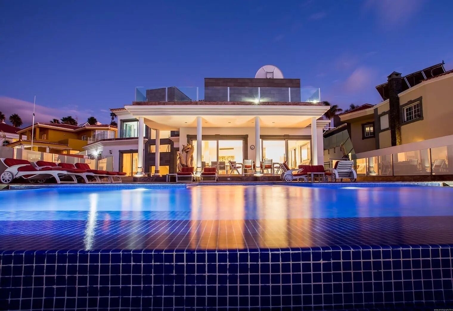 A modern hotel with a swimming pool, lounge chairs, and a clear view of the pool area.