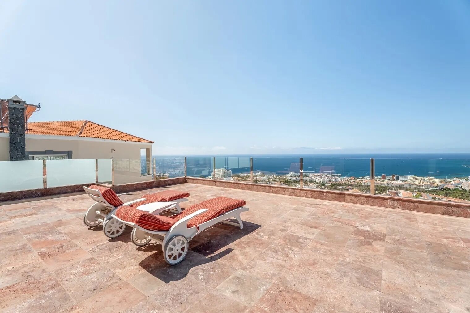 Una terraza en la azotea con dos tumbonas y vistas al mar.