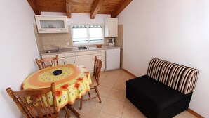 A compact kitchen with a dining table and chairs, a black sofa, and wooden ceiling beams. - Apartment 616/1479 (Istria - Rovinj), 500m from the beach (Rovinj)