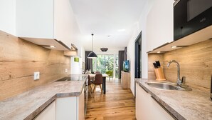 Een moderne keuken met houten vloeren, witte kasten en een eethoek met stoelen.