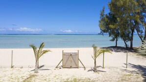 A beach with a wooden gate, palm trees, and a clear blue sky. - Villa Philibert (Surinam)