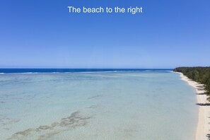 A beach with clear turquoise water, a sandy shore, and a line of trees. - Villa Philibert (Surinam)