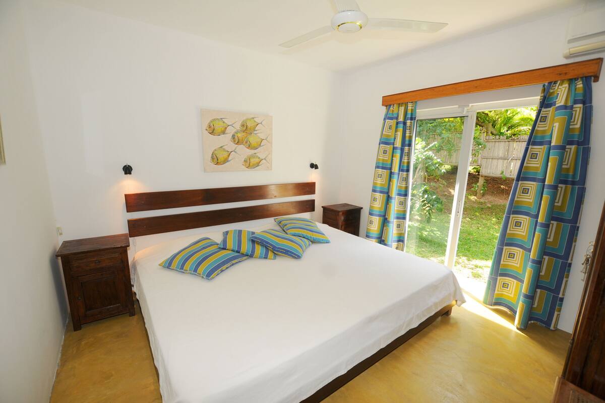Un dormitorio con cama, cabecera de madera y ventilador de techo.