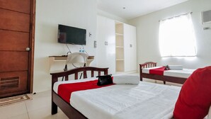 A hotel room with a bed, a desk with a chair, a television, and a wardrobe.